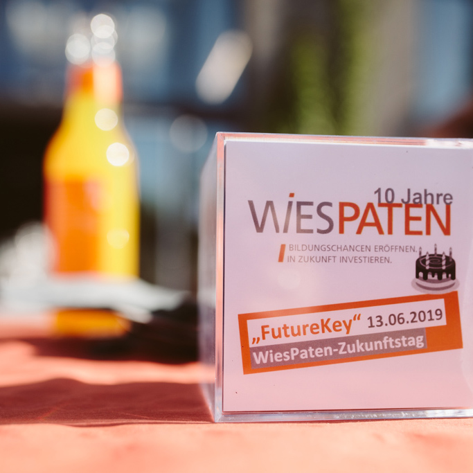WiesPaten 2022 | WiesPaten Sommerfest 2019. Glasflasche Limonade im Hintergrund und ein Plexiglaswürfel mit WiesPaten Design im Vordergrund.